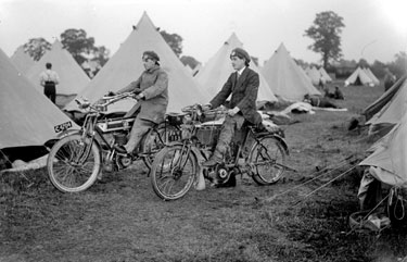 Two men on motorcycles, at camp