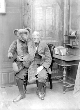 Teddy Bear by H.T.Y. sitting on Man's lap