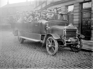 Charabanc (Daimler) with passengers, R Fletcher & Co building in background