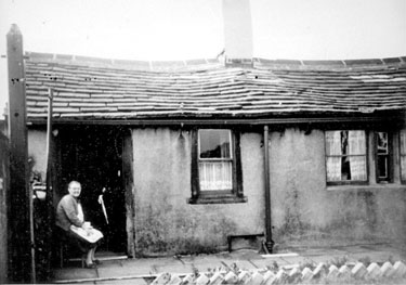 Mrs Berry sits outside her cottage in Low Fold, Scoles - demolished in 1966, the property was a 'low decker' with two rooms and minimal facilities, these types of homes were often built for colliers or quarry workers.