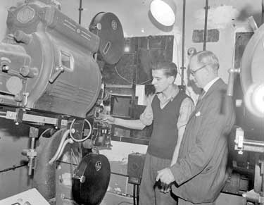 Men looking at Film Projector 	