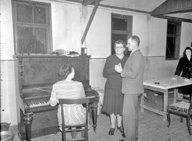 Woman playing piano, with couple dancing 	