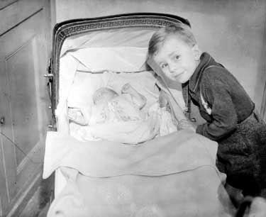 Boy with incubator baby in pram, Deighton 	