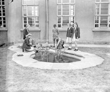 Schoolchildren looking at pond 	