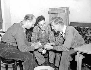 Three men peeling potatoes 	