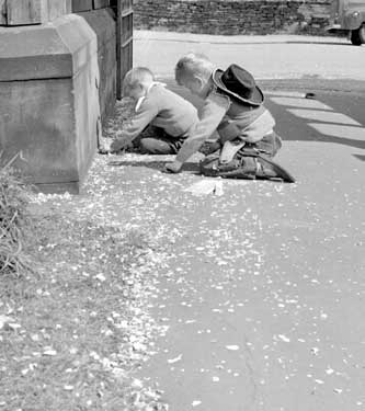 Children picking up confetti. 	