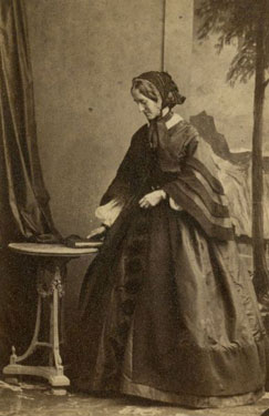 Portrait of a woman standing by a table.