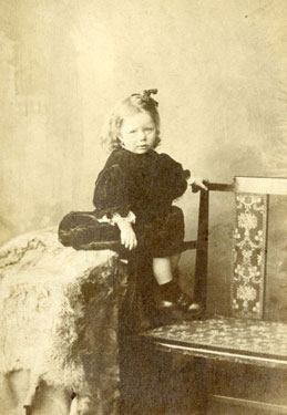 Portrait of a young child (girl) resting on a chair.
