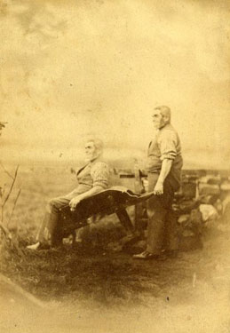 Two men, probably twins, with a wheelbarrow.