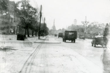 Wartime Archive of Reg Stone of Skelmanthorpe: Main Street with the Shwedagon Pagoda in the distance, Rangoon, Burma – Military jeeps entering Rangoon two weeks after its recapture.  