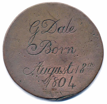 A bronze halfpenny coin which has been polished on both sides in order to produce a memento; on one side is the name G. Dale, with the date August 18th 1804 (which was a Saturday); on the other side is a scene with a boy or young man with a stick and hoop (or barrel), behind him a picket fence, and behind that a tree.