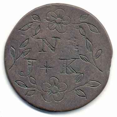 A bronze halfpenny (?) coin which has been smoothed on both sides in order to produce a love token; one side has the letter N above the letters J and K, the whole surrounded by simple flower and leaf motifs; the other side is covered by a similar floral design - a single sprig with leaves and three flowers.