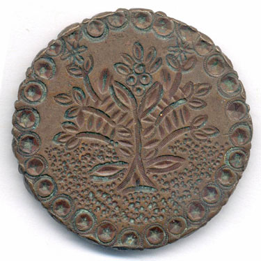 A bronze 1764b Swedish 2 öre coin adapted to make a love token; the obverse has a crown above two arrows, the value (2 öre) and the mintmark S.M. - the details have been emphasised and an outer circle of round depressions has been stamped; the reverse has a stamped ornamental tree or shrub within a similar circle. This is a coin of King Adolph Frederick: the king died of digestion problems on 12 February 1771 after having consumed a meal consisting of lobster, caviar, sauerkraut, kippers and champagne, which was topped off with 14 servings of his favourite dessert: semla served in a bowl of hot milk. He is thus remembered by Swedish school children as "the king who ate himself