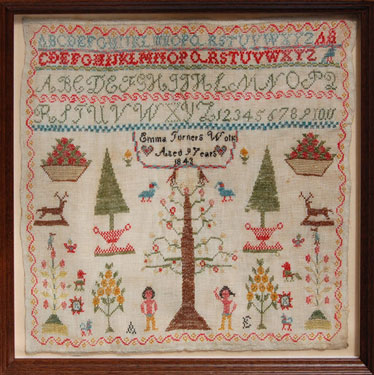 A framed sampler signed Emma Turner, aged 9, 1843. Central design of Adam and Eve, Tree of Knowledge, birds, animals, alphabet and numbers. 