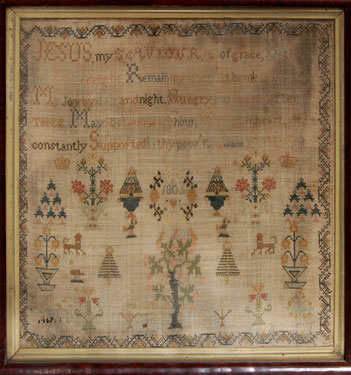 A framed sampler signed Jane Wilson in 1805. With religious text and floral motifs.