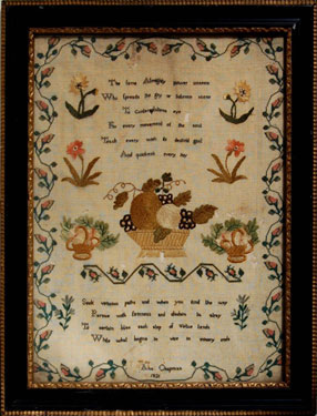 A framed sampler signed by Ann Chapman 1821. Central motifs of fruit bowl, flowers with trailing floral border and moral text.