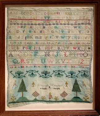 A framed sampler signed by Elizabeth Whitehead 1797. Alphabet, numbers with trees, flowers and birds