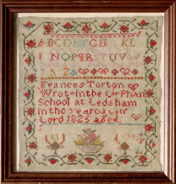 A framed sampler signed Frances Torton at the orphanage in Ledsham, North Yorkshire in 1825. Alphabet above a bowl of flowers, with a floral border. The orphanage at Ledsham was erected on the instruction of Lady Betty Hastings in the 18th century.