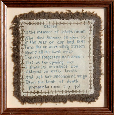 A framed sampler in memory of Joseph Mann who died in 1841. Religious text, border detail and tassled edging.