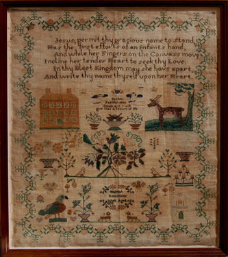 A framed sampler signed Hannah Ramsden 1833. Elaborate design, religious text, flowers, birds, cherubs, deer, a house, a tree, border of strawberries.
