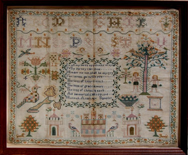 A framed sampler signed Hannah Armitage. Elaborate design, alphabet and numbers, religious text, birds, flowers, buildings, dogs Adam and Eve, Tree of life, serpent and cherubs. 
