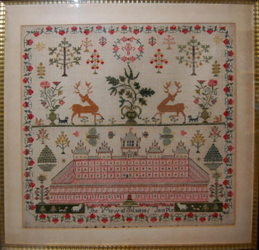 A framed unsigned sampler. With trees, vases of flowers, dogs, and a squirrel above 'The View of Solomon's Temple'; with a strawberry border.