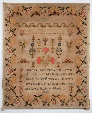 A mounted but unframed sampler, made by Caroline Riley in 1848; with religious text and alphabet, with floral motifs above and a 'honeysuckle' border.