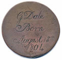 View: ka00015 A bronze halfpenny coin which has been polished on both sides in order to produce a memento; on one side is the name G. Dale, with the date August 18th 1804 (which was a Saturday); on the other side is a scene with a boy or young man with a stick and hoop (or barrel), behind him a picket fence, and behind that a tree.