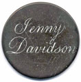 View: ka00026 A bronze George II halfpenny coin which has been polished on both sides in order to produce a love token; the reverse simply shows the name Jenny Davidson - the engraving is of a good standard, and the letters have been emphasised by the application of a white substance; the obverse has been polished and left blank, but the vague outline of George II remains.