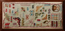View: ksp00021 A framed sampler consisting of different designs dotted around; including a kettle, flowers, leaves, boxes. Edged with pink textile. Embroiderer unknown,
