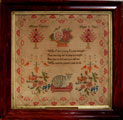 View: ksp00042 A framed sampler signed Mary Thornton aged 9. Poem, cat on cushion, flowers birds, surrounded by floral border.