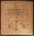 View: ksp00044 A framed sampler signed Mary Sykes 1844. Religious text in centre surrounded by flowers, trees, dogs, two cherubs and bordered by flowers.