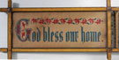 View: ksp00045 A framed sampler, simple design, text 'God bless our home', row of flowers above text.